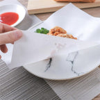 Oil-absorbing cooking paper sheets on a plate with fried food, reducing grease.