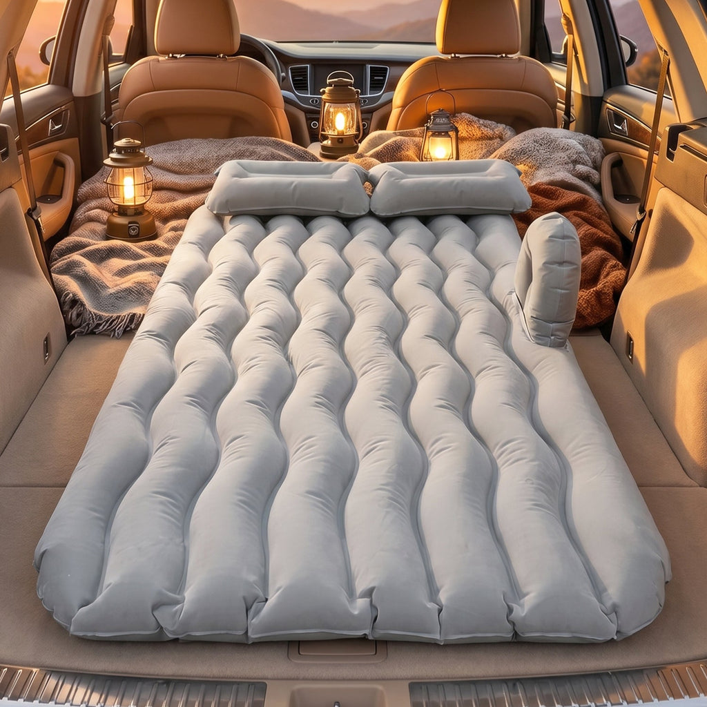 Car air mattress set up for camping, with lanterns in background
