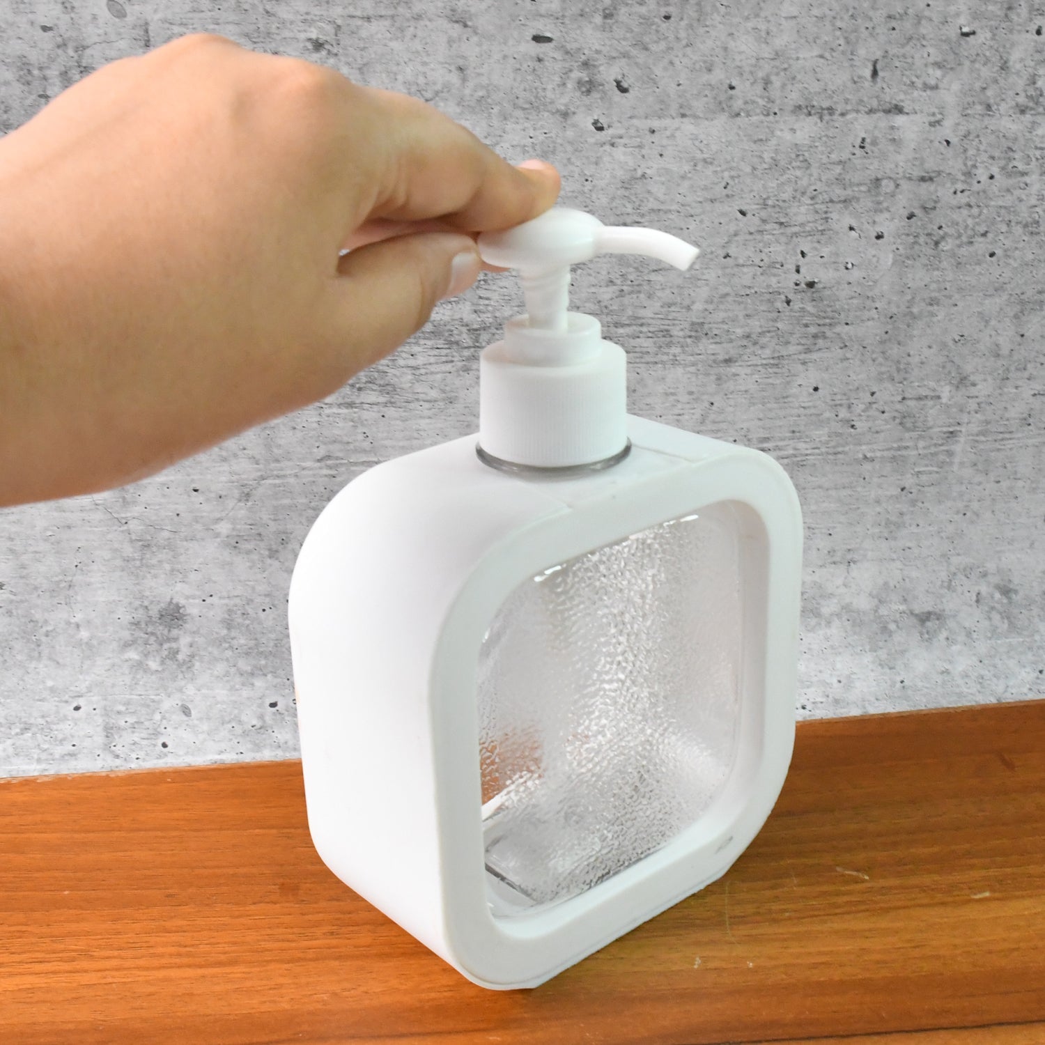 Angled shot of the clear plastic pump bottle, showing its sleek profile.