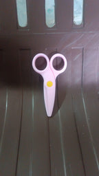 A child happily using the child-safe plastic scissors for an art project.