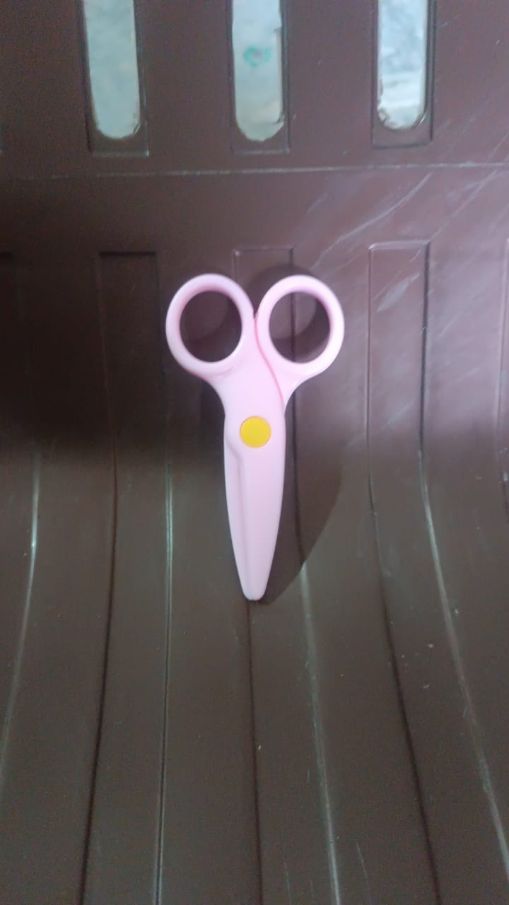 A child happily using the child-safe plastic scissors for an art project.