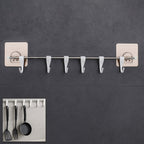 Stainless steel utensil hanger rail with 6 hooks installed on a clean kitchen wall, ready for use.