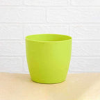 Round plastic flower pots displayed in a garden setting, suitable for all weather.