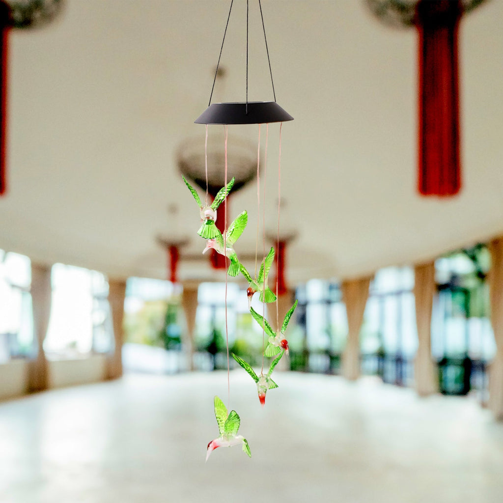 Decorative solar powered hummingbird wind chime hanging in garden