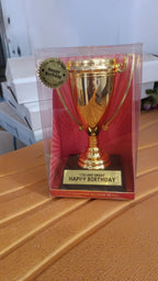 Front view of golden birthday trophy with printed label on sturdy base