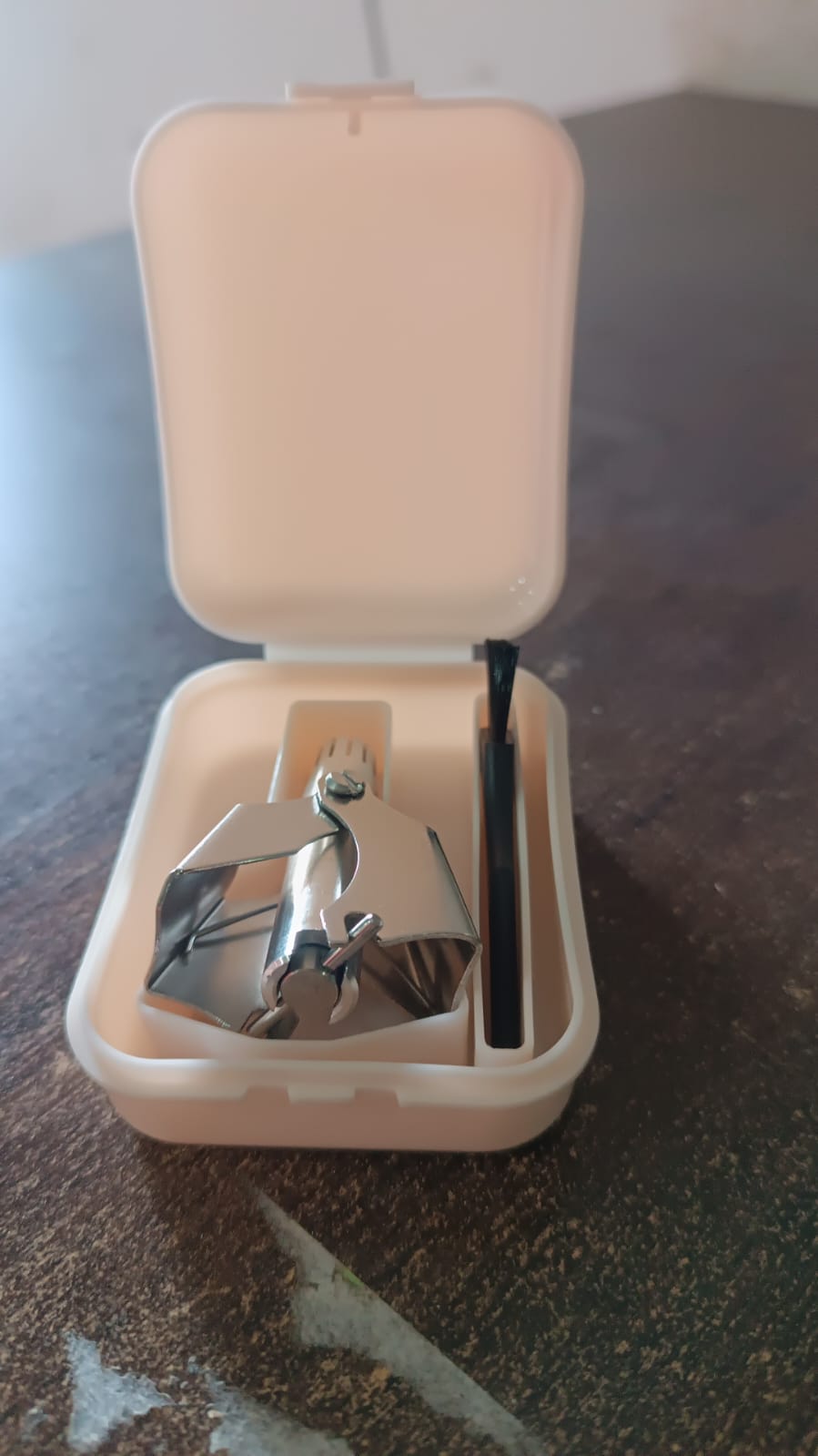 The complete nose hair clipper set, including the trimmer, brush, and protective plastic case.