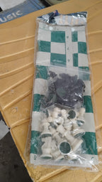 Portable chess set with foldable board and plastic pieces on flat surface