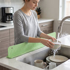 User washing dishes with the silicone water splash guard in action.