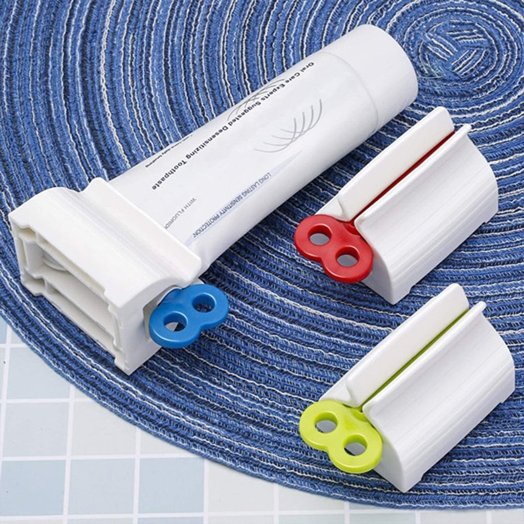 White toothpaste squeezer with an upright stand, holding a tube on a light surface.