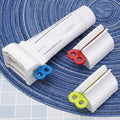 White toothpaste squeezer with an upright stand, holding a tube on a light surface.