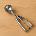 Stainless steel ice cream scoop with spring-loaded release mechanism.