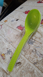 Single black plastic kitchen ladle resting on a rustic wooden table, ready for use.