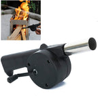 Man using a hand-cranked charcoal grill fan to ignite BBQ coals outdoors.