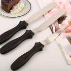 A flat stainless steel pallet knife from the set, ideal for smoothing large surfaces on cakes.