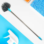 Extendable cobweb cleaning brush with stainless steel handle reaching a high ceiling.