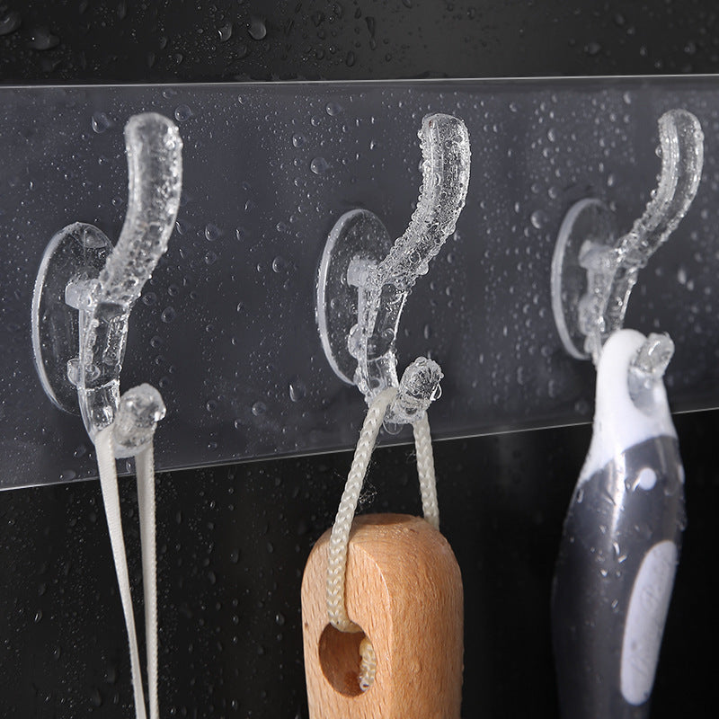 A single transparent wall hook securely mounted on a tiled kitchen wall, holding a towel.