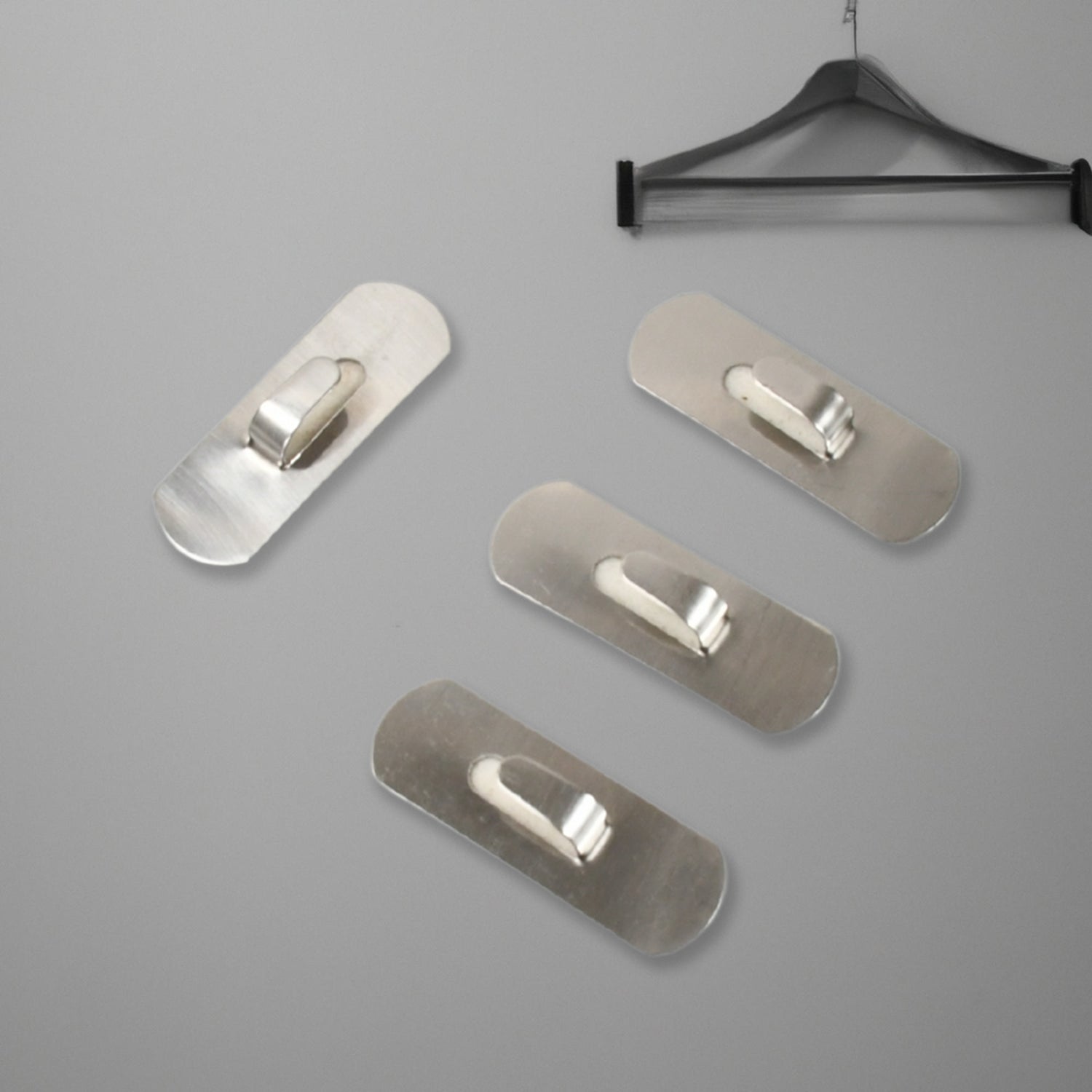 Two stainless steel self-adhesive hooks neatly holding towels in a modern bathroom.