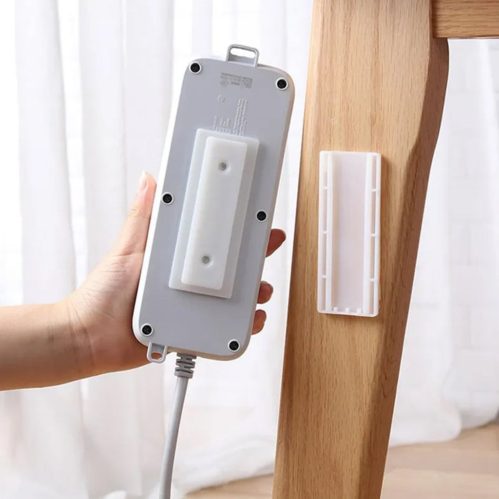 Self Adhesive Plug Organizer on a white wall, neatly holding a power strip.