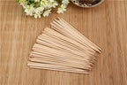 Hand holding a natural bamboo skewer with perfectly grilled meat.