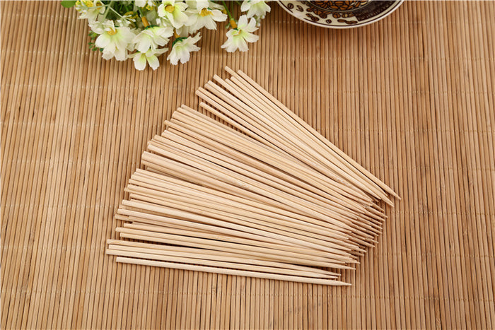 Hand holding a natural bamboo skewer with perfectly grilled meat.
