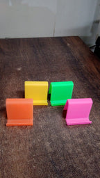 Mobile phone resting securely in angled plastic phone stand on table