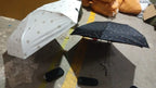 Lifestyle shot of a compact umbrella being used in a city setting during light rain.