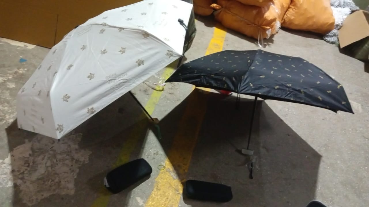 Lifestyle shot of a compact umbrella being used in a city setting during light rain.