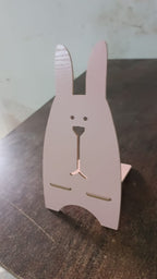 The wooden rabbit mobile stand securely holding a smartphone for easy viewing.