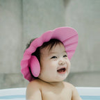 Pink baby shower cap with adjustable strap, designed for splash-proof hair washing.