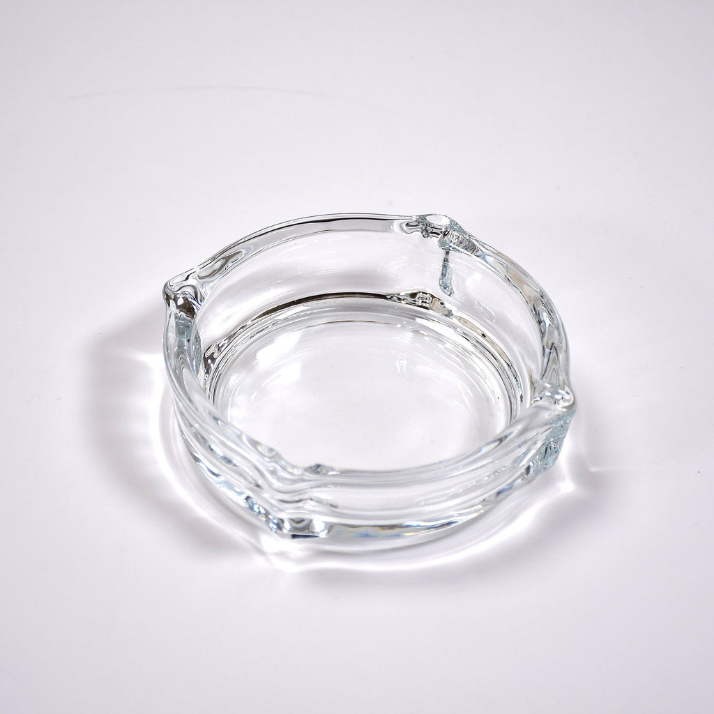 Clear glass ashtray featuring a classic round shape and convenient cigarette slots.