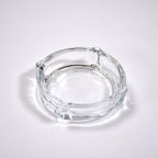 Clear glass ashtray featuring a classic round shape and convenient cigarette slots.