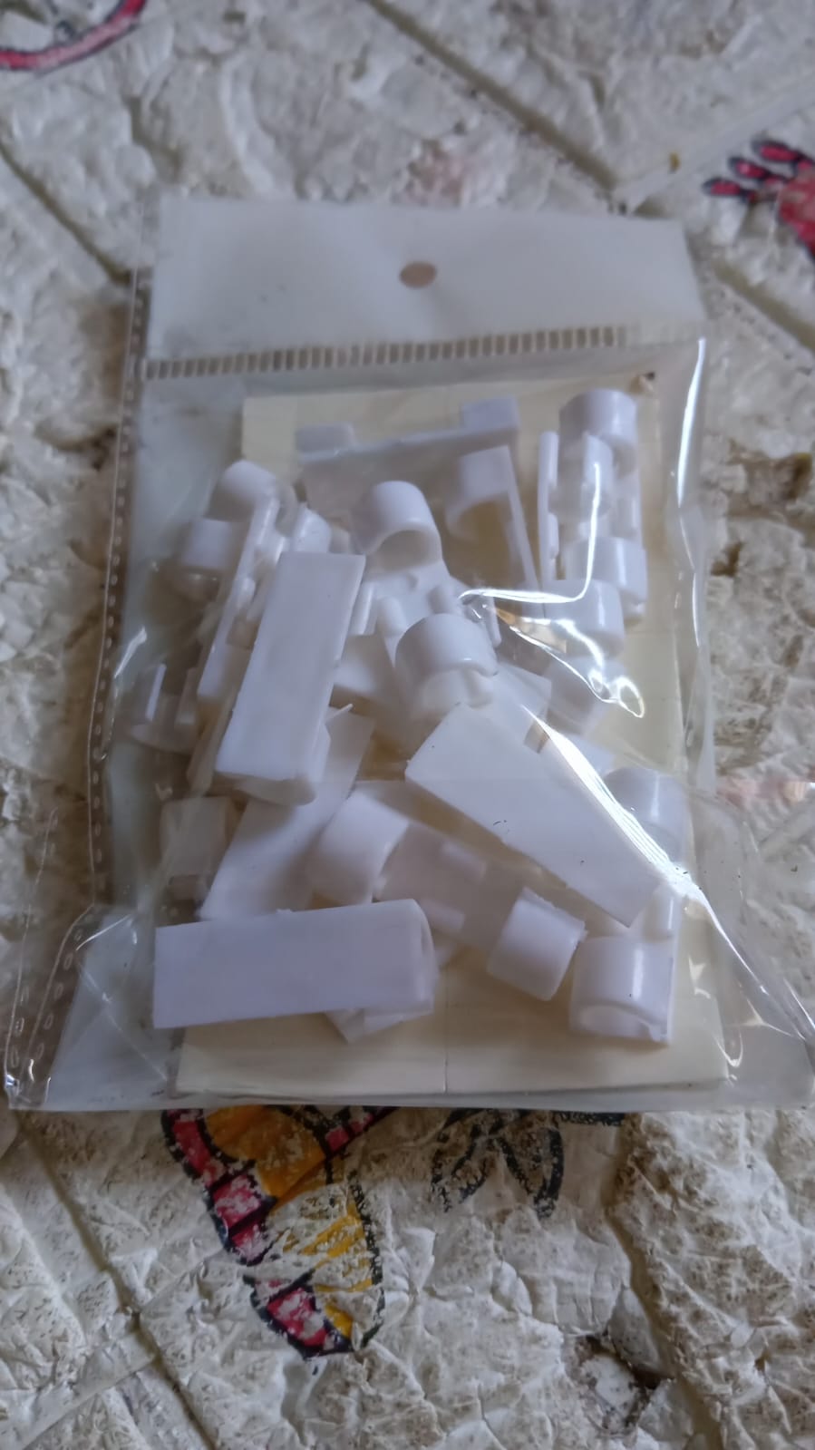 An array of cables neatly organized with adhesive plastic cable clips against a light-colored wall.