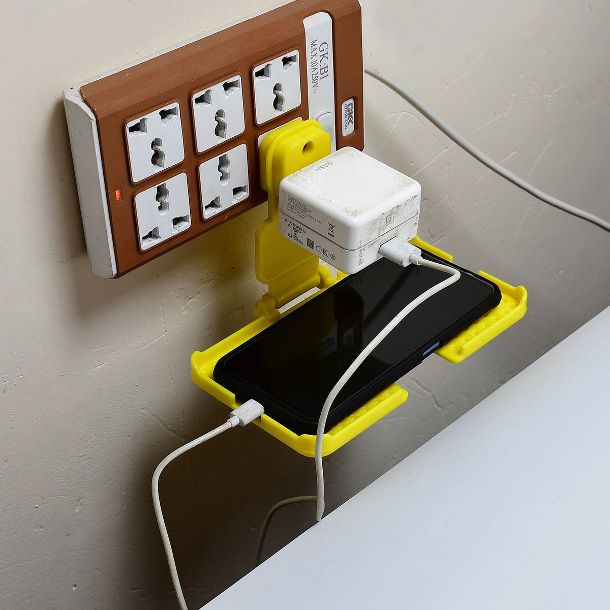 Yellow Mobile Charging Wall Holder securely plugged into a power socket.
