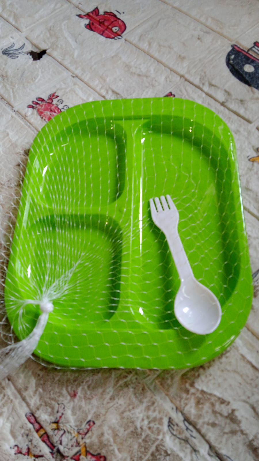 Side view of the reusable 3-compartment food plate with a spoon.