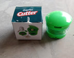 Garlic crusher with a detachable green container for easy collection and cleaning.
