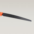 Hand pruning saw being used to cut a tree branch in a garden.