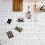 Stainless steel wall hooks neatly holding towels and robes in a bathroom.