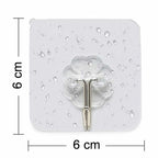 Individual small stainless steel adhesive hook with its protective backing visible before installation.
