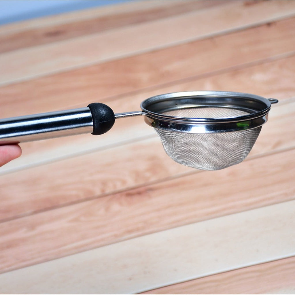 Stainless steel fine mesh strainer being used to filter tea.