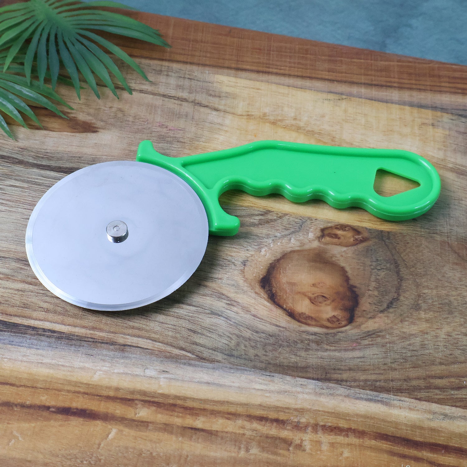Side profile of the Quickslice versatile pizza and sandwich cutter on a rustic wooden surface.
