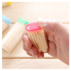 Several high-quality bamboo toothpicks neatly arranged beside their dispenser box.
