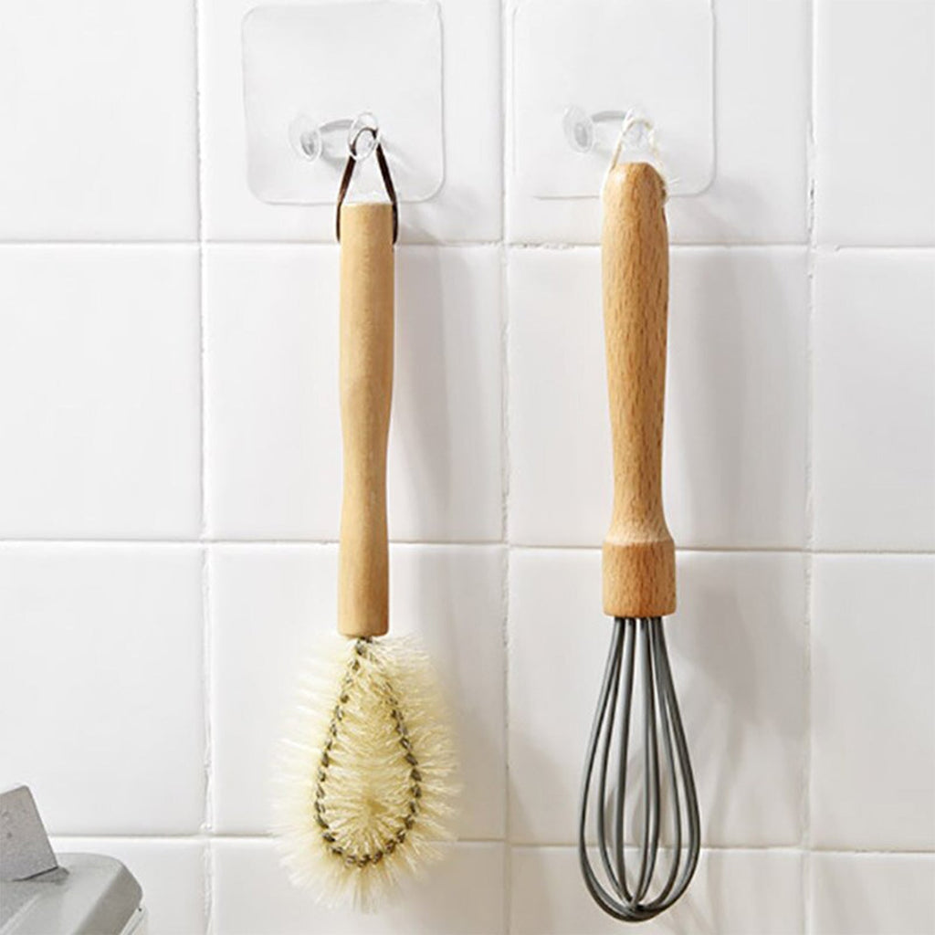 Clear adhesive wall hook securing an umbrella and bags without damaging the wall surface.