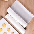 Roll of non-stick parchment paper for baking and cooking on a wooden surface.