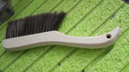 Hand holding a soft bristle brush, gently cleaning a sofa surface to remove dust.