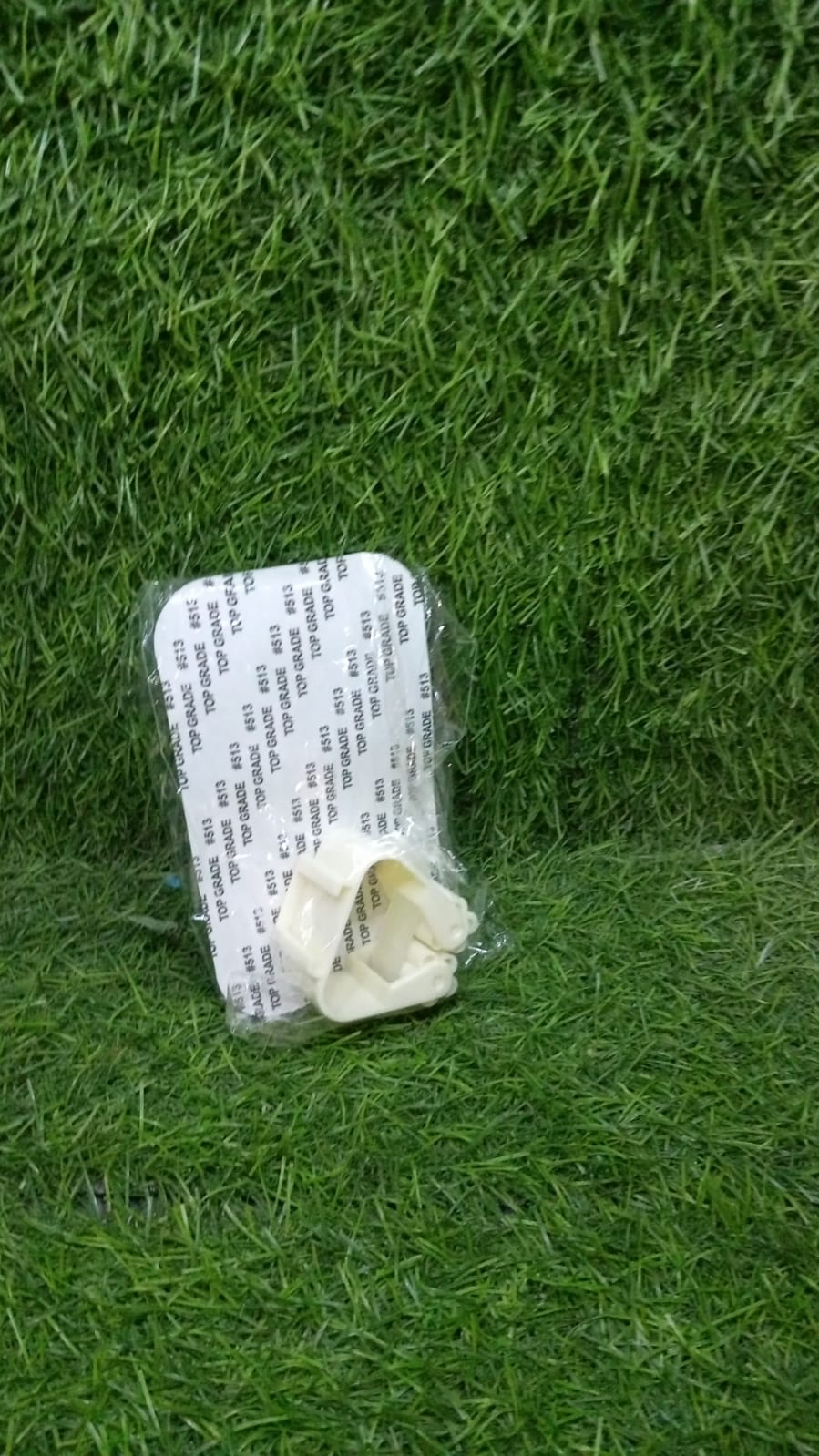 The self-adhesive mop holder securely gripping a broom handle on a wall.