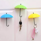 Multicolor umbrella wall hook securely holding various keys and a hat on a light surface.