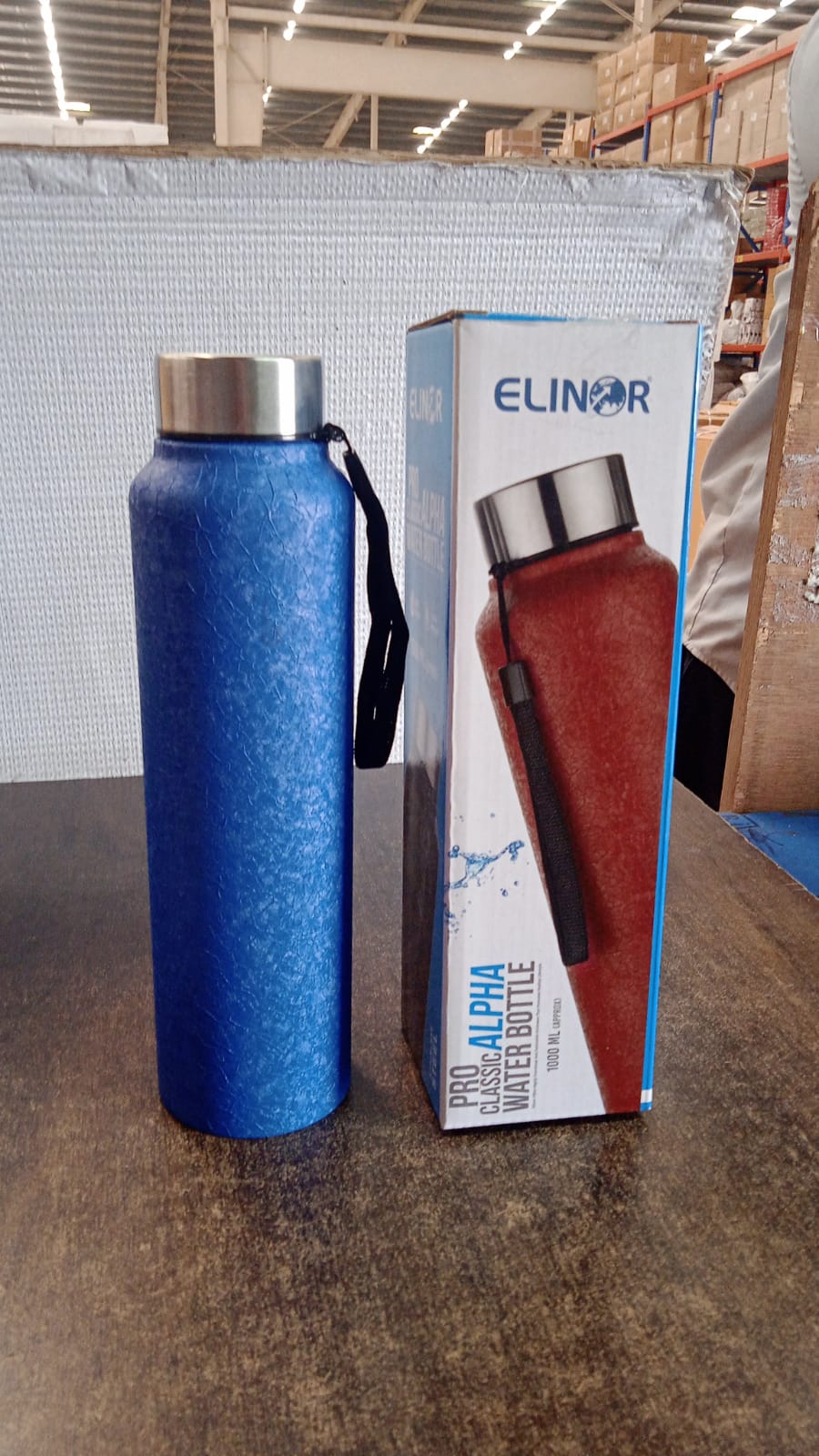 Person carrying black stainless steel water bottle with green cap outdoors