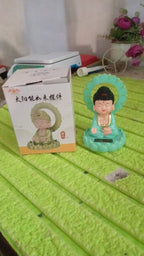The solar Buddha statue on a car dashboard, bringing calm to daily commutes.