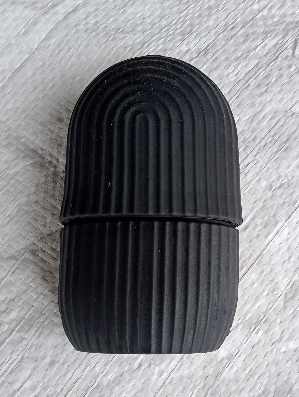 Black face ice roller placed on a textured grey cloth, showing its sleek design.
