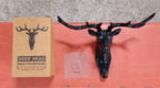 Three deer head wall hooks in black, white, and grey mounted on a wall.